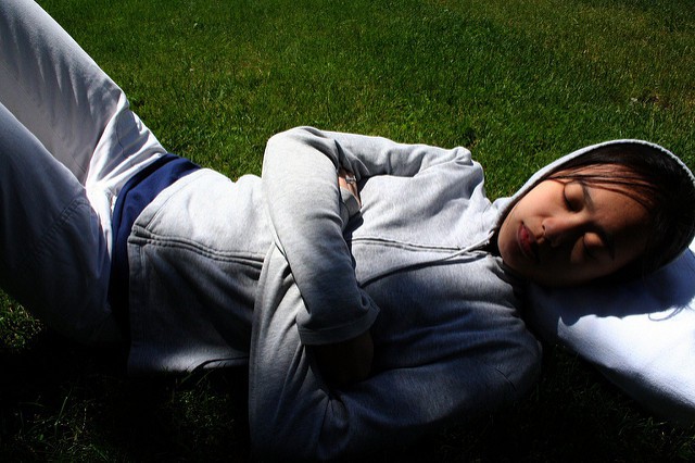 Une jeune femme sportive fait la sieste sur l'herbe.