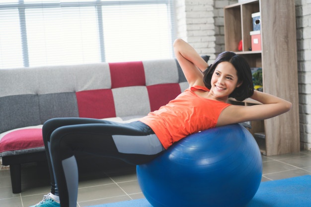 Une femme fait du renforcement musculaire sur un swiss ball