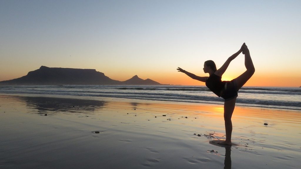 Une femme réalisant une séance de yoga pour débutant sur la plage