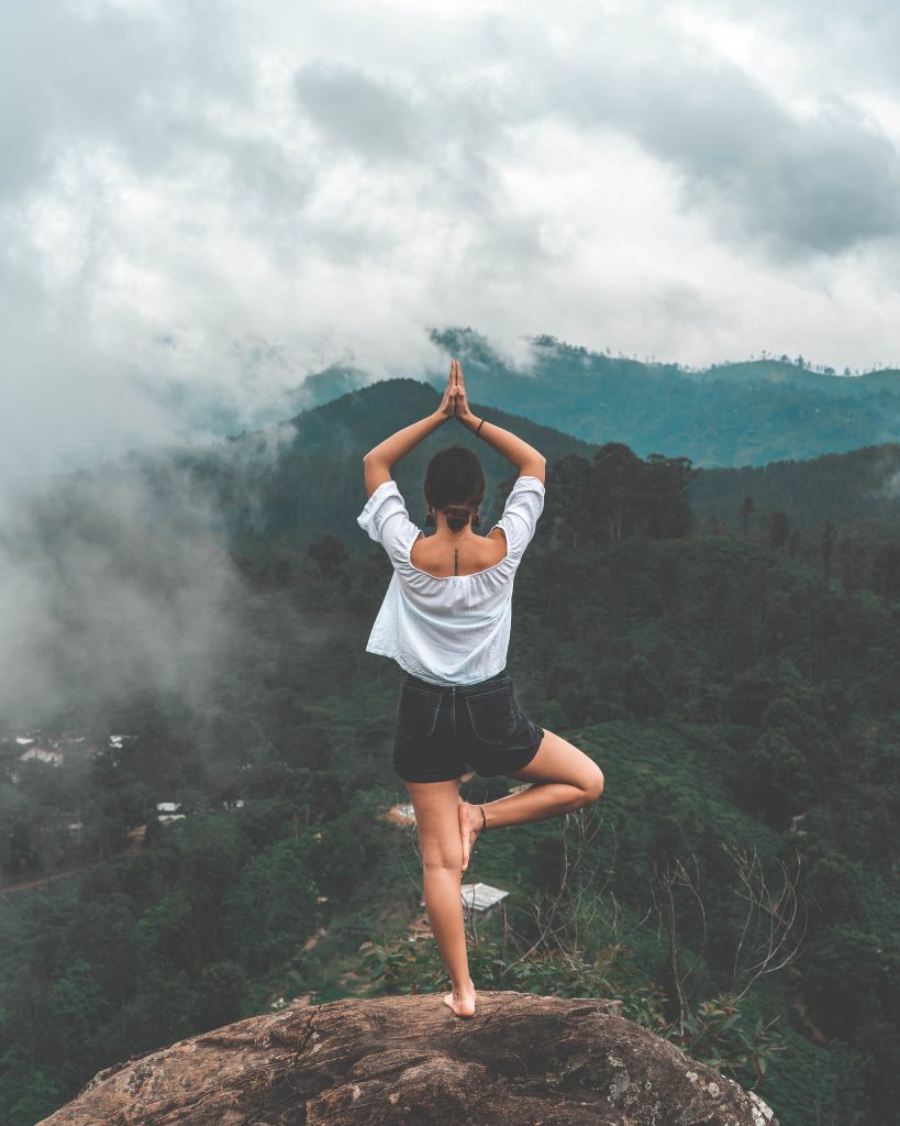 Une femme réalisant un exercice de Yoga pour le dos en pleine nature pour se détendre