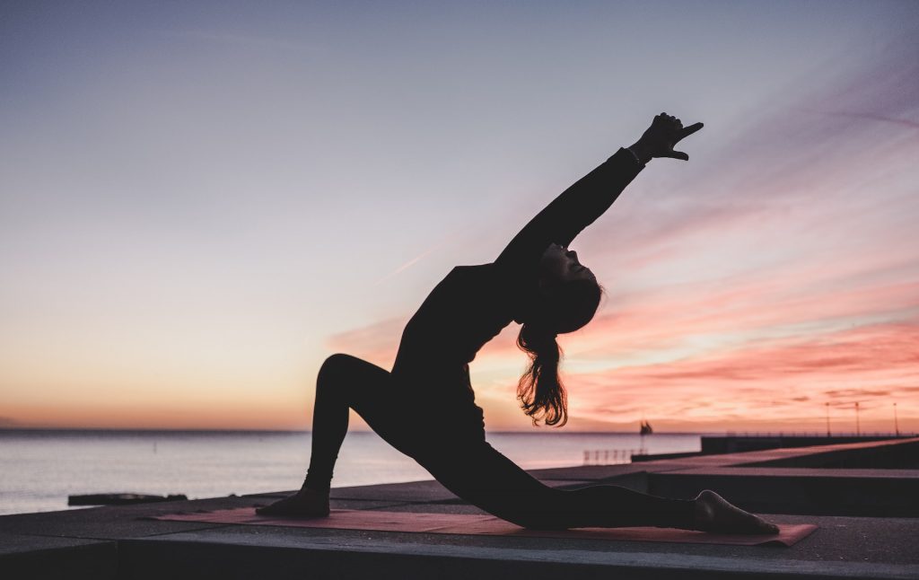 une femme réalisant un exercice de yoga en extérieur