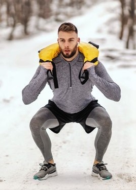 une homme s'entrainant en extérieur avec un bulgarian bag lors de sa préparation physique