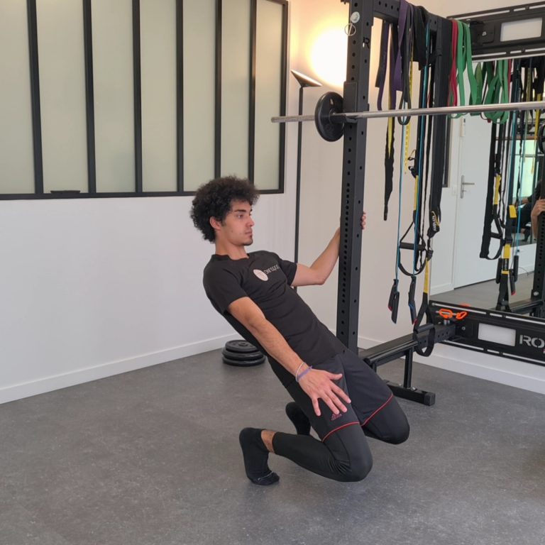 Dans un homegym, en tenue de sport et avec un tee-shirt ownsport, notre coach réalise le sissy squat.