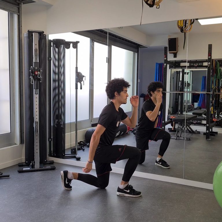 Fentes sautées face à un miroir dans une salle de sport privée.