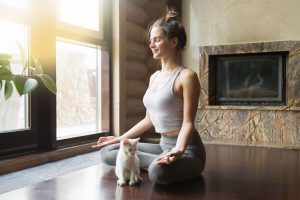 Une sportive pendant une séance de yoga avec son chat.
