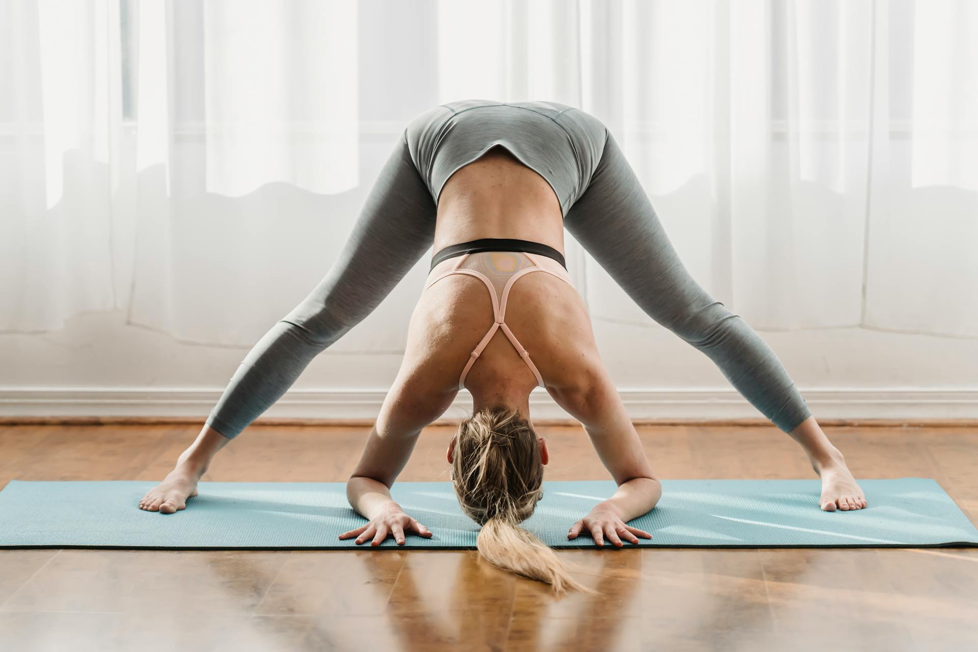 Une yogi réalise Prasarita Padottanasana sur un tapis de yoga.