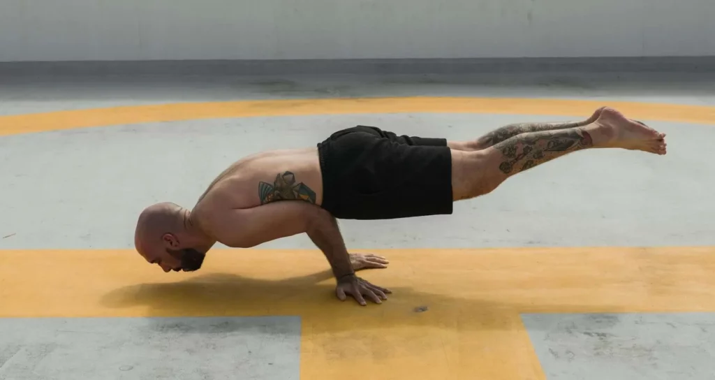 En short, un homme se tient en équilibre sur les mains, un exercice de yoga difficile appelé posture du paon.