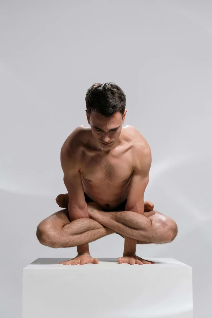Un homme concentré tient un exercice de yoga : le kukkutasana.
