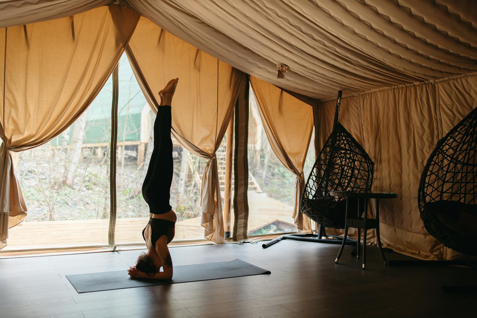 Une professeure de yoga effectue la posture sur la tête depuis son espace de pratique.