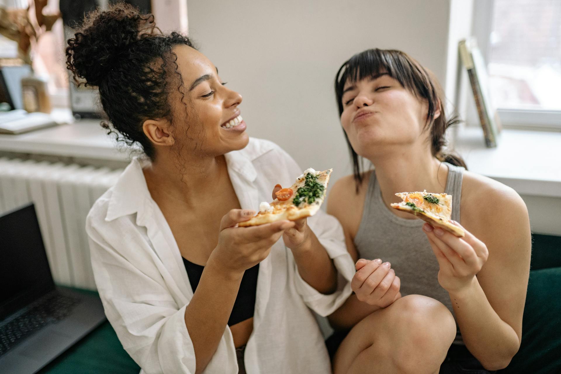 Deux femmes mangent une pizza avec des légumes.
