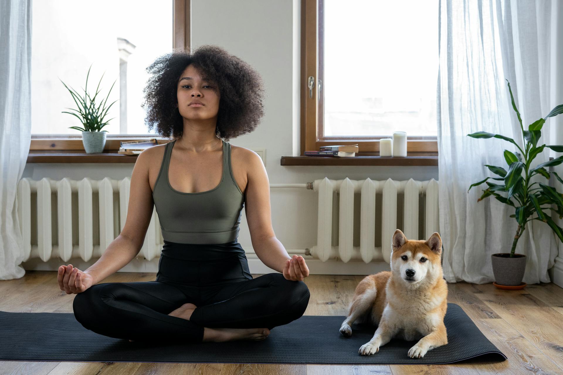 Une femme fait du sport à la maison avec son chien.