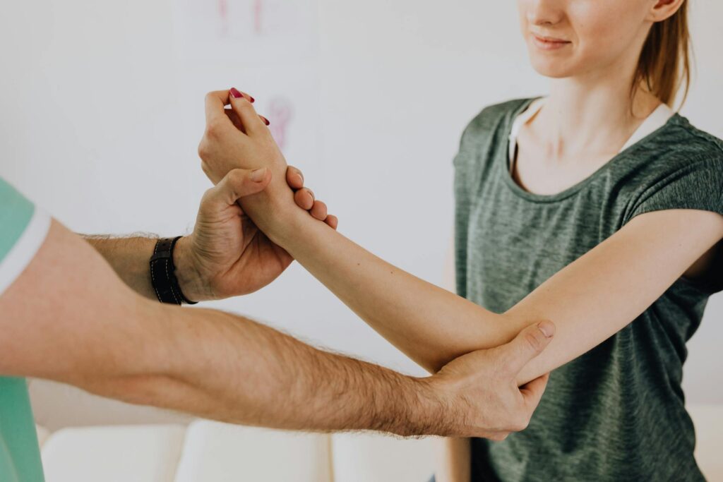 Une femme souffrant de tendinopathie se fait palper le bras par un médecin.