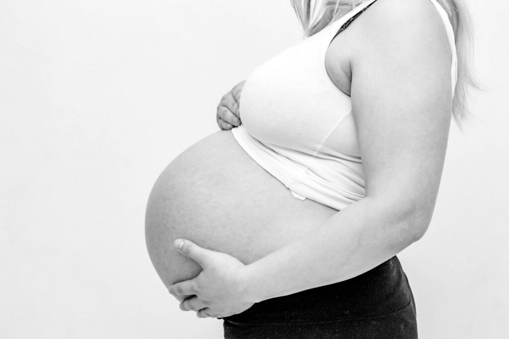 Une femme enceinte en tenue adaptée se tient le ventre.