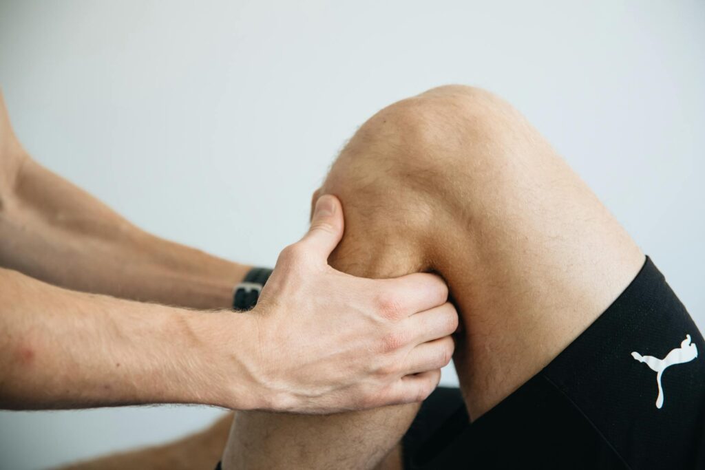 Un sportif blessé au genou subit une manipulation de la part d'un rééducateur.