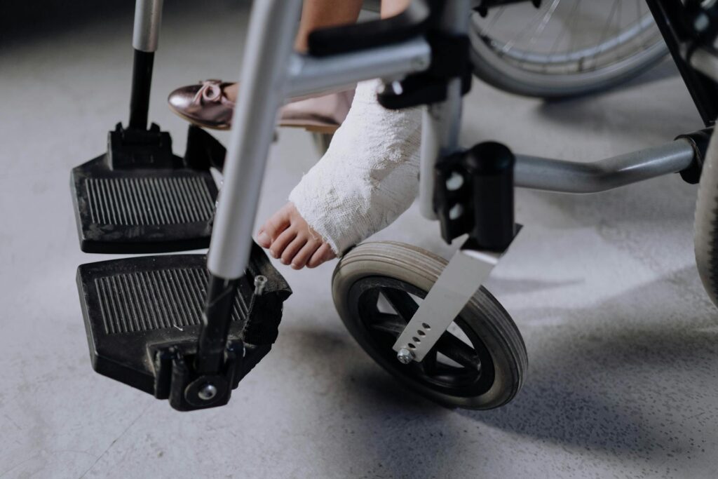 Une personne en fauteuil roulant porte un plâtre au pied gauche.