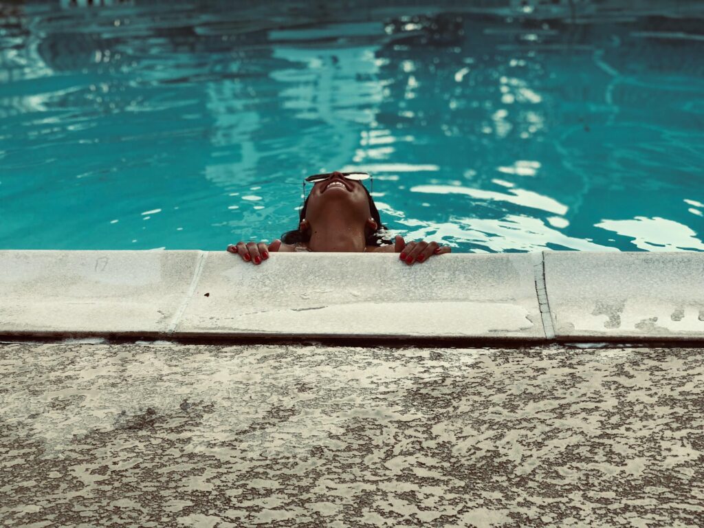 Une femme se tient au rebord d'une piscine en regardant en l'air.