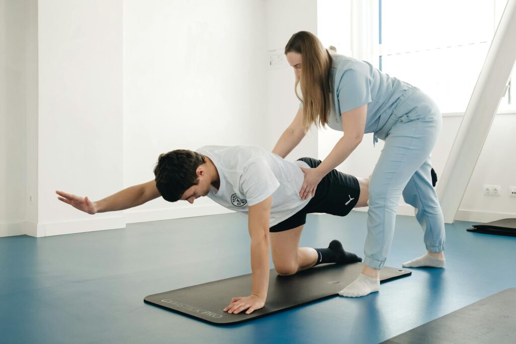 Une coach en réathlétisation post blessure aide son élève à faire du gainage.