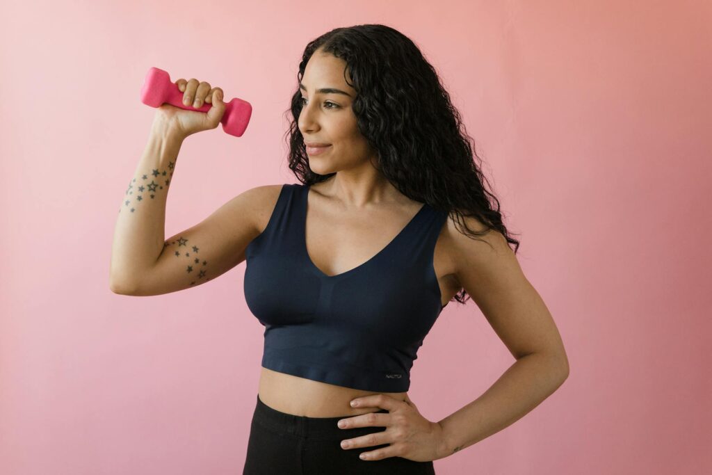 Une femme sportive fait du renforcement du coude avec une haltère.