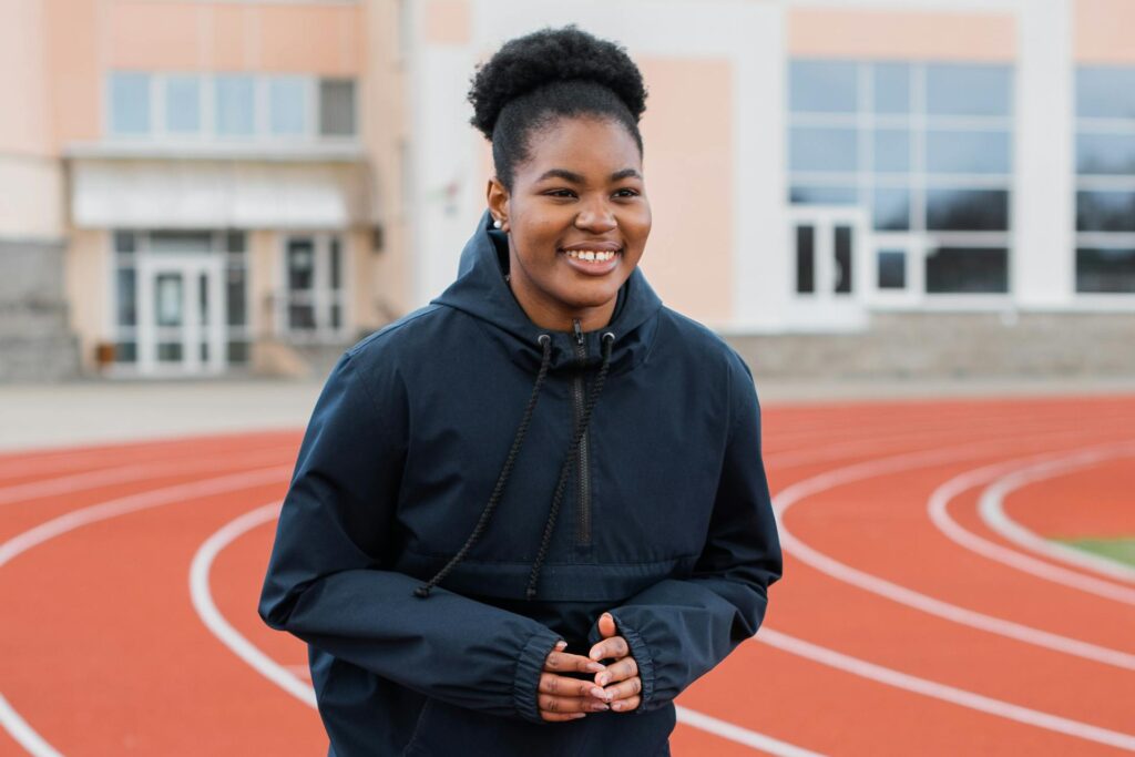 Une femme sur une piste d'athlétisme porte une veste de sport coupe-vent.