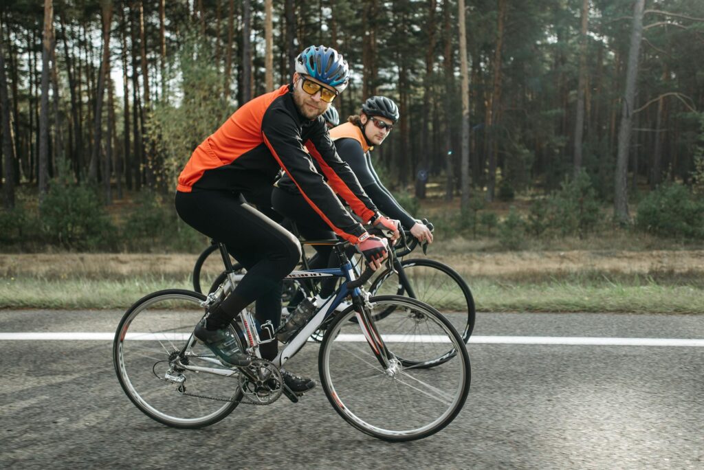 Deux cyclistes sur leurs vélos sur une route le bord d'une forêt.