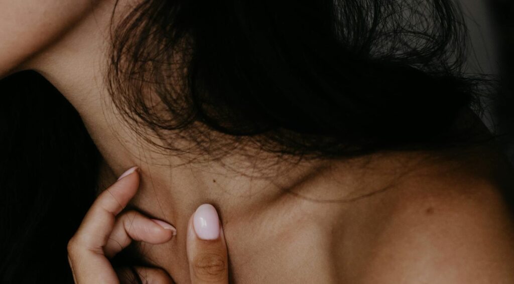 Une femme touche sa clavicule.