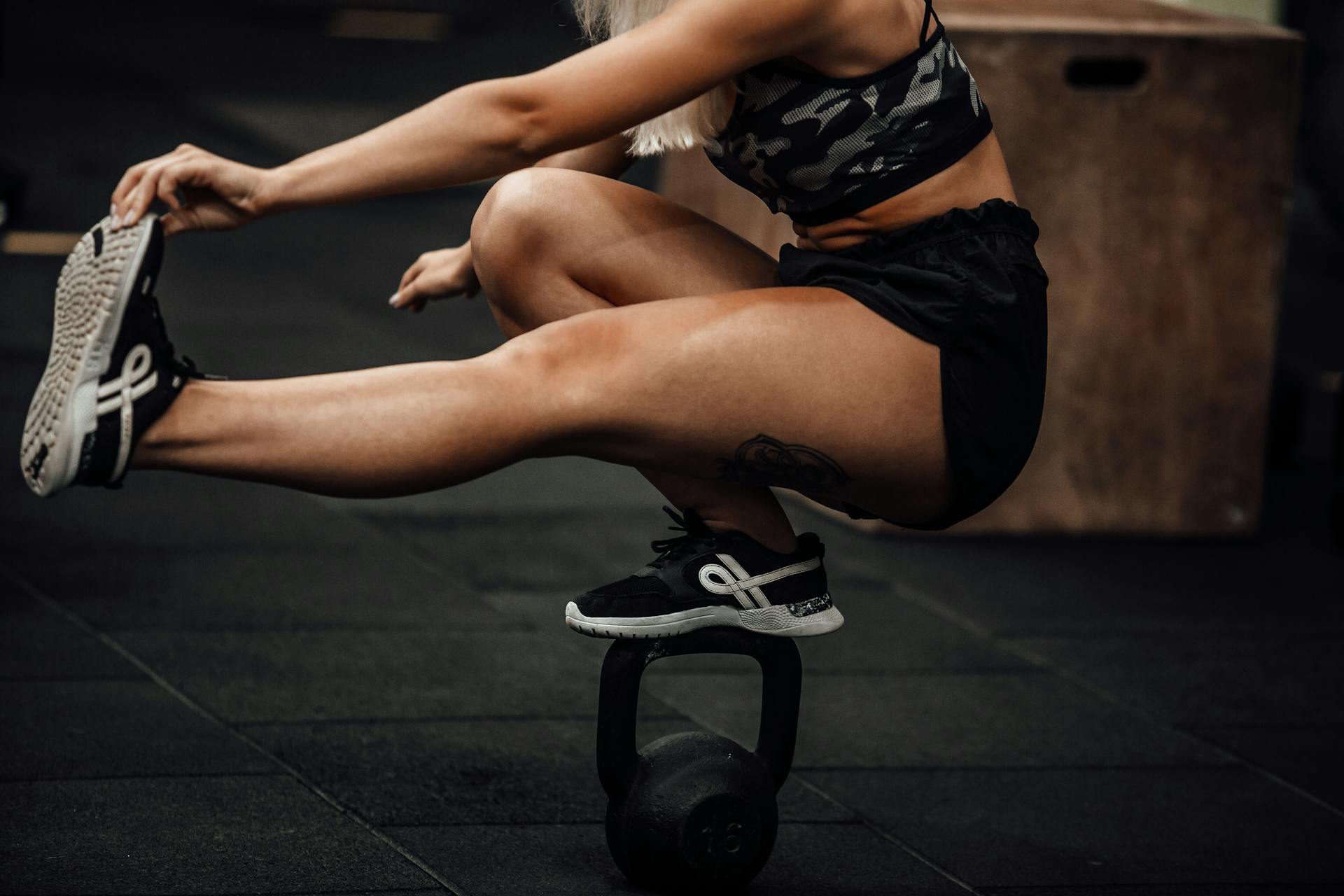 Une femme en tenue de sport réalise un pistol squat.