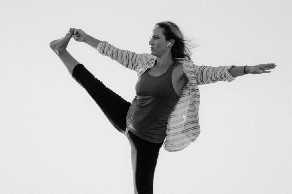 Une femme en train d'effectuer Utthita hasta padangusthasana en plein air.