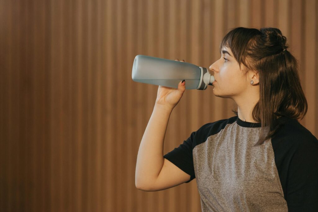 Une femme en tee-shirt boit de l'eau.