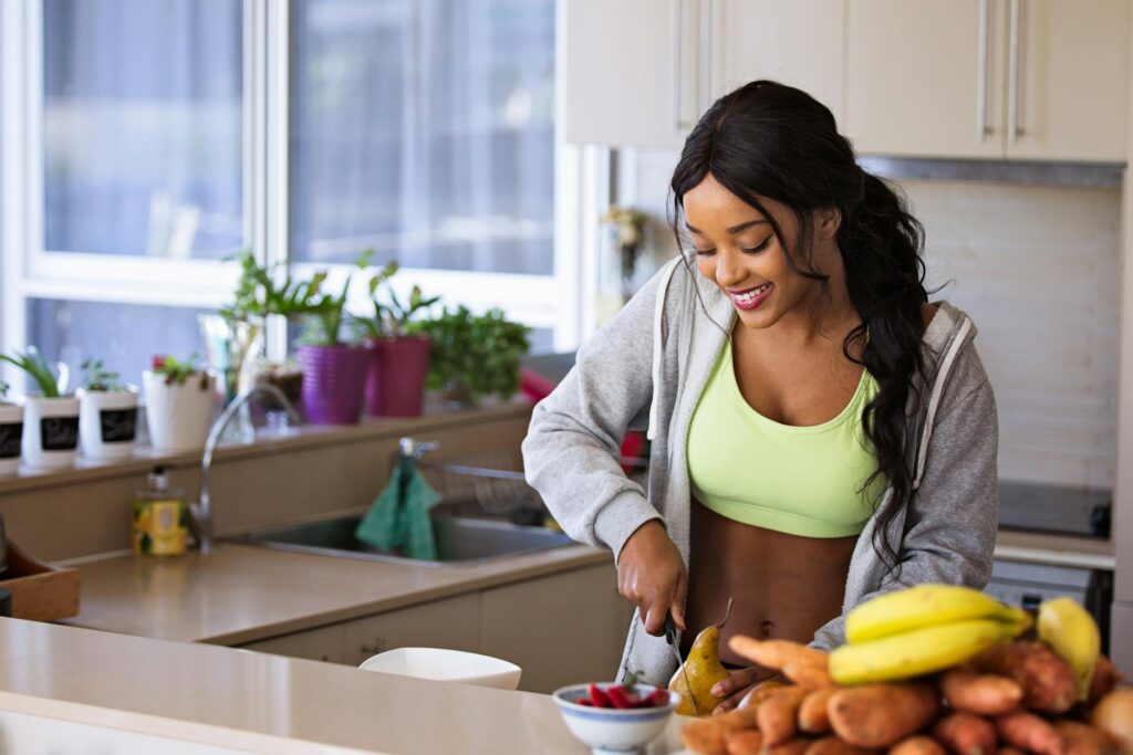 Une femme en tenue de sport se prépare une salade de fruits.