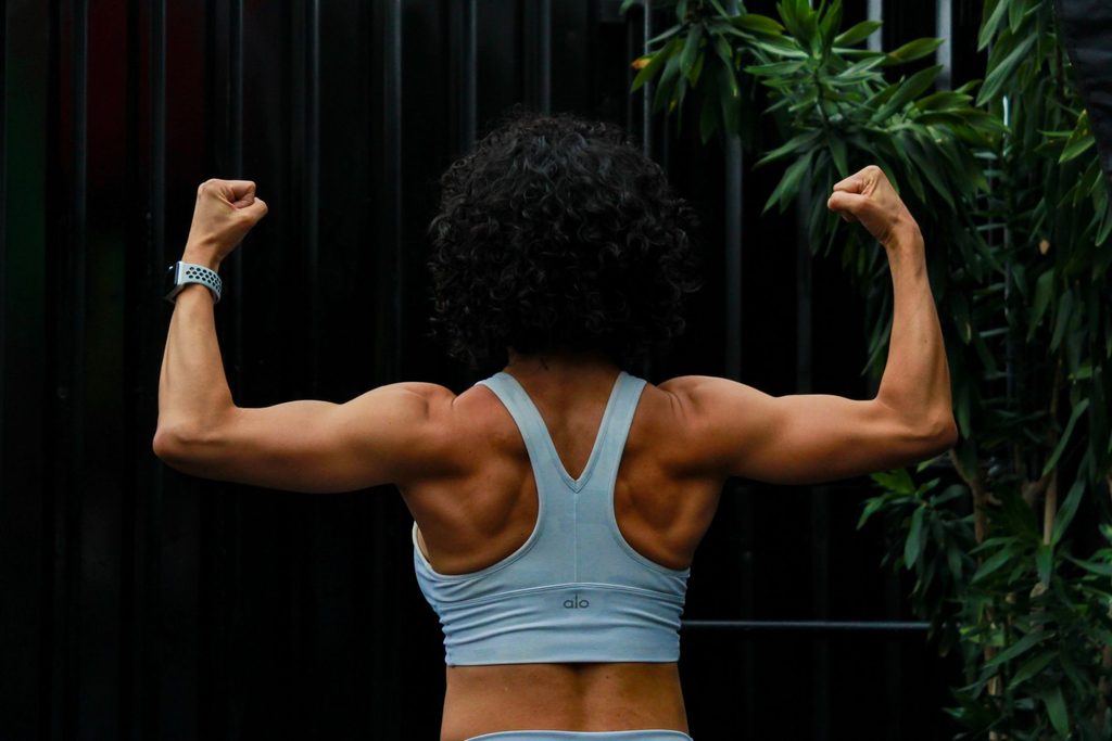 Une femme montre les muscles de ses bras et de son dos.